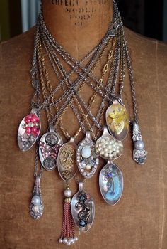 a bunch of spoons that are hanging on a wall with some charms attached to them