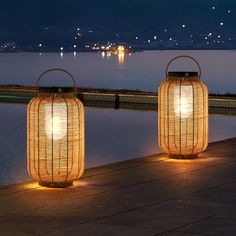 two lanterns sitting next to each other near the water