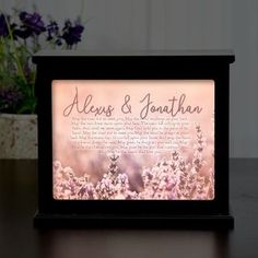 an illuminated photo frame with the words, alex & jonathan on it and flowers in the background