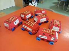 a group of toy firetrucks sitting on top of an orange table in a classroom