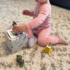 a baby sitting on the floor playing with toys