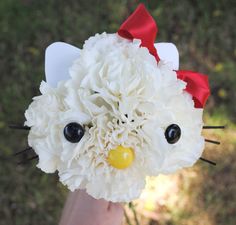 a hand holding a fake hello kitty made out of paper mache and tissue flowers