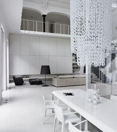 a white dining room table with chairs and a chandelier hanging from the ceiling