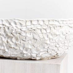 a white bowl sitting on top of a wooden block