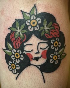 a close up of a tattoo on the leg of a woman with flowers in her hair