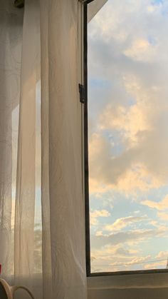 the cat is sitting on the window sill looking out at the sky and clouds