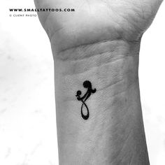 a black and white photo of a person holding a small tattoo on their wrist with the letter s in it