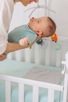 a woman is holding a baby in her arms while she plays with the crib