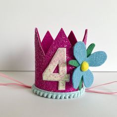 a purple birthday crown with a flower on it and the number four written in white