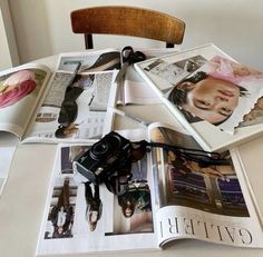 an open magazine sitting on top of a table filled with pictures and other items next to a wooden chair