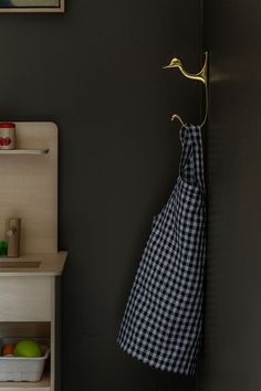 a black and white checkered apron hanging from a hook on a wall in a kitchen