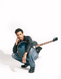 a man kneeling down with a guitar in front of his face and leaning on the ground