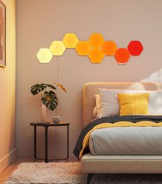 a bed with yellow and orange pillows in a bedroom next to a wall mounted hexagons