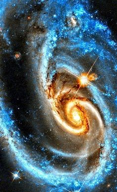 an image of two spirals in the sky, with stars around them and one is blue