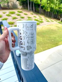 a person holding up a coffee mug on a blue bench