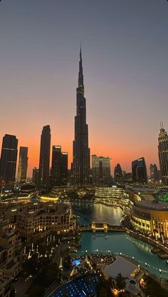 the city skyline is lit up at night, with skyscrapers in the foreground