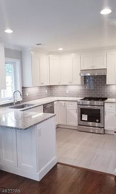 an empty kitchen with white cabinets and stainless steel appliances in the middle of the room