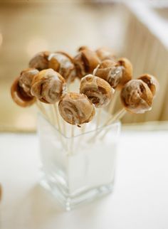 a glass vase filled with cinnamon rolls on top of a table