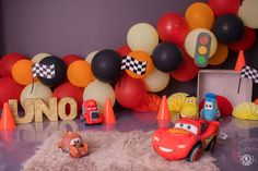 a birthday party with cars and balloons on the wall, including an orange race car