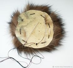 a white hat with brown fur and needles attached to the top, on a white surface