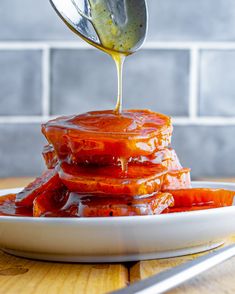 a spoon drizzling ketchup onto some food on a plate