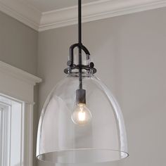 a clear glass dome light hanging from a ceiling fixture in a room with white walls