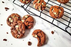 chocolate cookies are cooling on a rack with other cookies in front of them and one cookie has been broken