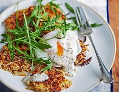 a white plate topped with hash browns and fried eggs on top of green leafy greens