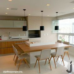 an open kitchen and dining room area with white tile flooring, wooden table and chairs