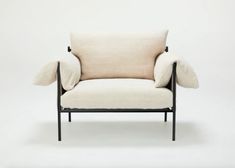 a white chair with black legs and a beige pillow on it's backrest