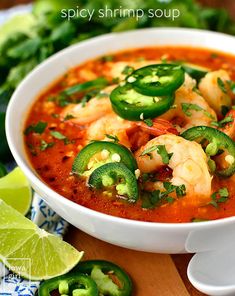 a white bowl filled with shrimp and jalapenos on top of a wooden table