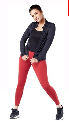 a woman in red pants and black top is posing for the camera with her hands on her hips