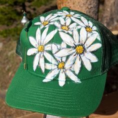 a green hat with white daisies painted on it