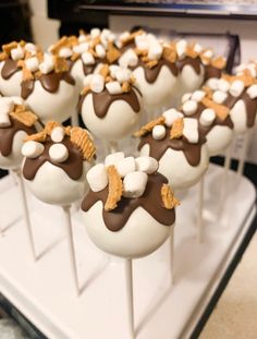 chocolate and marshmallow pops are arranged on a white tray, ready to be eaten