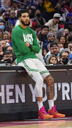 a man sitting on top of a bench in front of a crowd at a basketball game