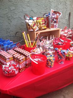 a red table topped with lots of candy and candies on top of it's sides