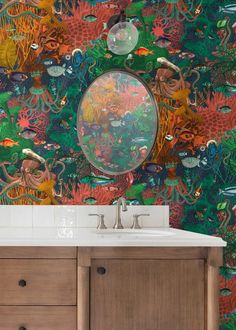 a bathroom sink under a mirror in front of a wallpapered background with fish and corals