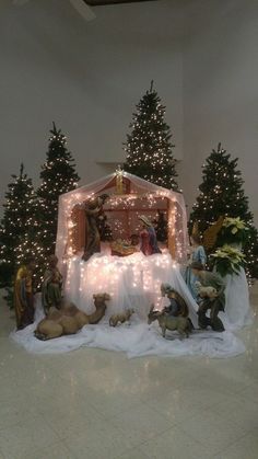 a nativity scene is displayed in the middle of a room decorated with christmas lights