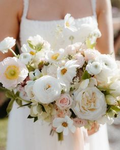 a bride holding a bouquet of white and pink flowers