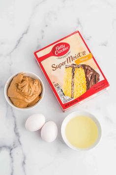 ingredients for cake sitting on top of a white marble counter next to an open box of cake mix