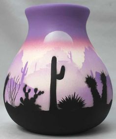 a purple vase with black and white designs on it's sides is shown in front of a backdrop of cacti