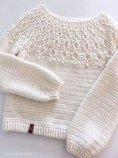 a white knitted sweater sitting on top of a table