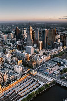 an aerial view of a city with lots of tall buildings and train tracks in the foreground