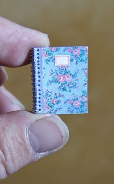 a person holding a tiny notebook in their left hand with flowers on the front and back