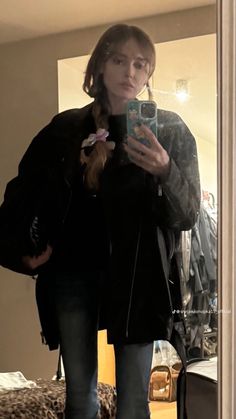 a woman standing in front of a mirror holding a cell phone