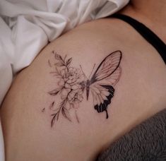 a woman's stomach with a butterfly and flowers tattoo on the side of her belly