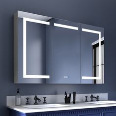 a bathroom vanity with two mirrors and lights on the wall above it, along with blue cabinets