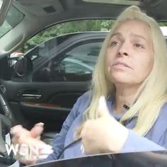 a woman sitting in the driver's seat of a car giving a thumbs up