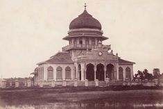 an old photo of a building with a clock on it's tower and water in front