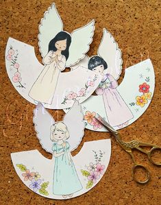 paper angel cut outs with scissors and flowers on the corkboard floor next to them